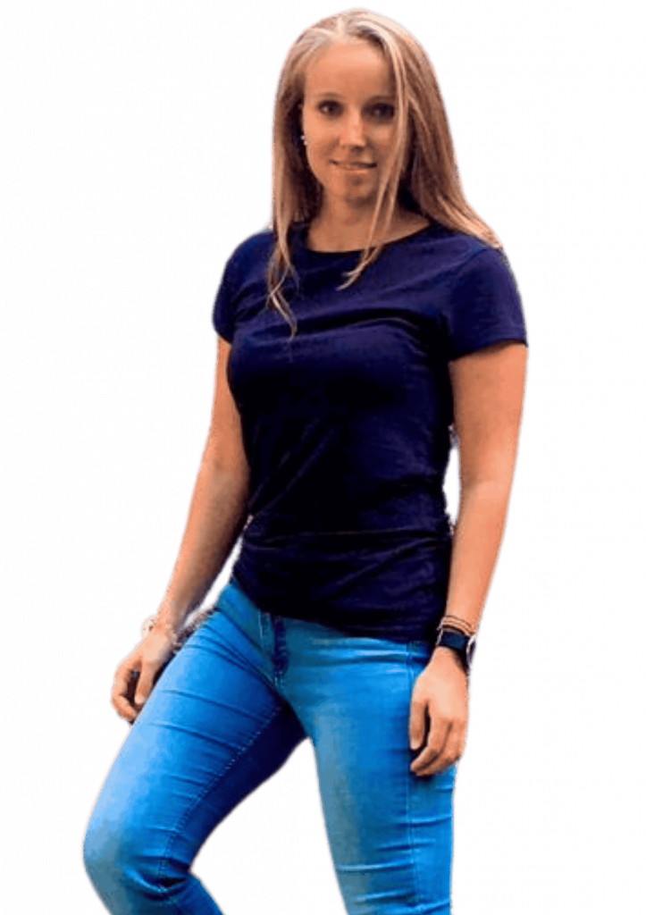 Blonde, schlanke Frau in dunklem Tshirt und Jeans steht mit offener Körperhaltung lächelnd mit angewinkeltem Bein.